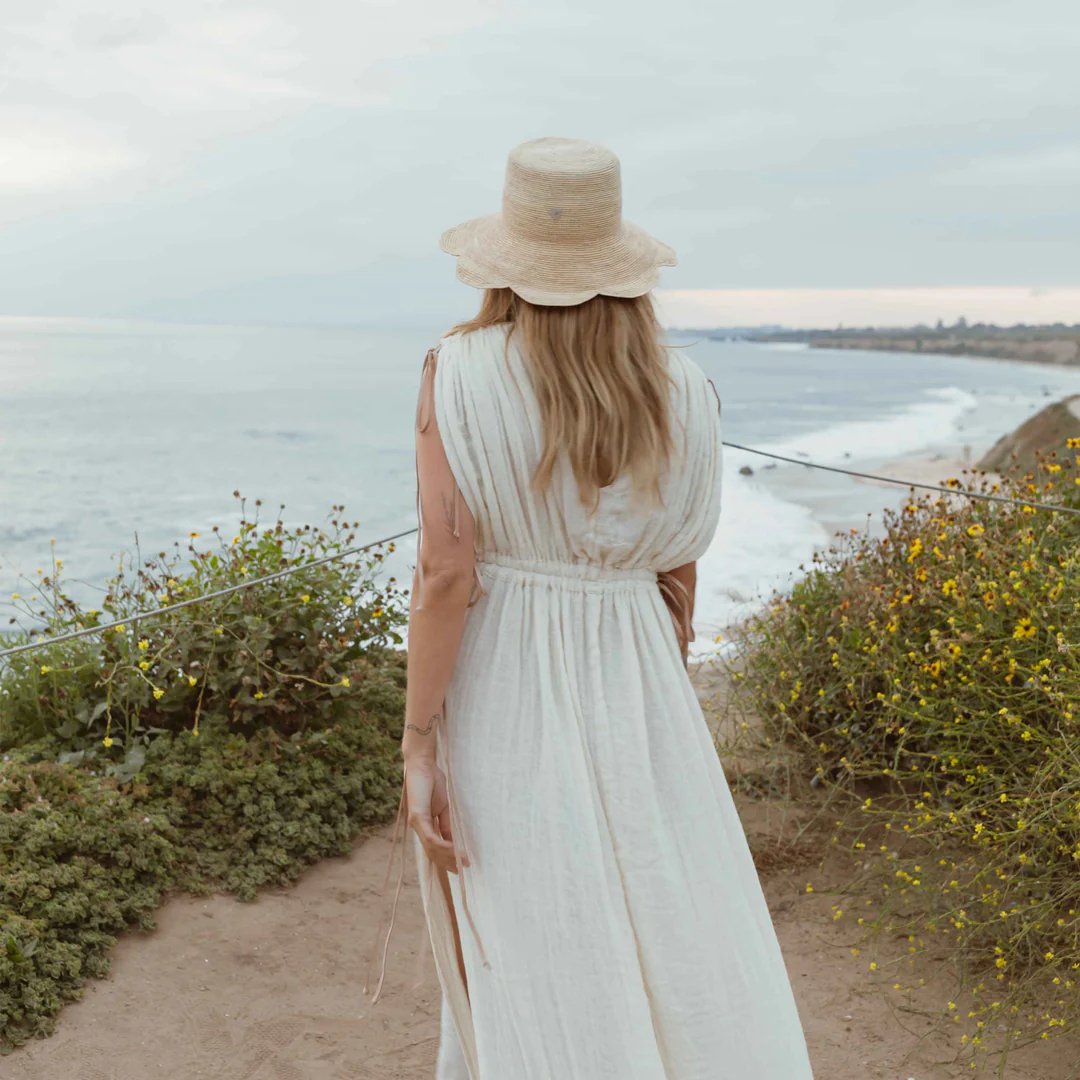 women's freya packable scallop crochet bucket hat in natural on model outside by ocean behind view