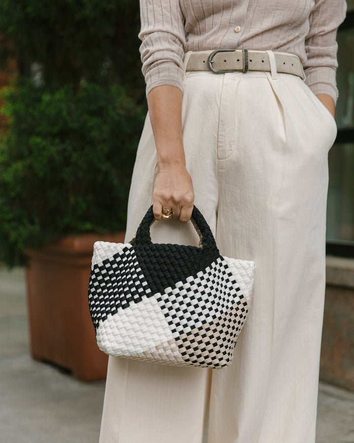 Woman holding the Naghedi St. Barths small tote graphic geo in palermo print. Black, white and tan woven print bag.