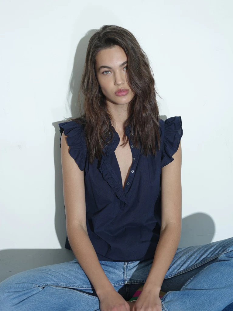 Model wearing the Xirena women's brenna top in navy with jeans