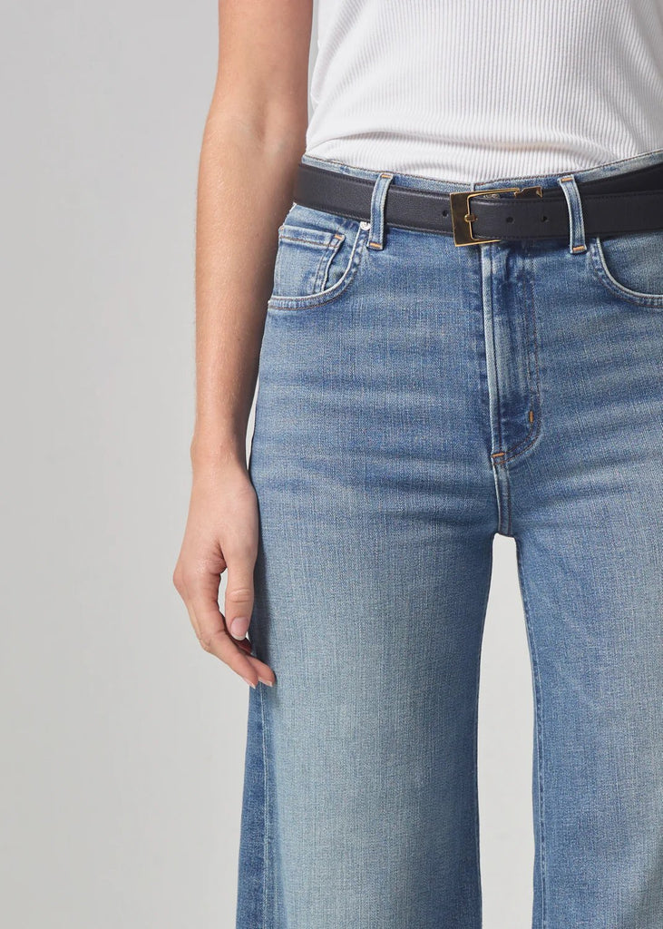 Citizens of humanity lyra crop wide leg in abliss with raw hem styled on model. Up close image of jeans styled with belt. 