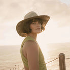 Freya Mesquite, vented natural crown paired with upturned cowgirl brim in black and natural, trimmed with hand-dyed cotton ribbon. Styled on model outside by ocean.