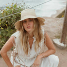 freya packable scallop crochet bucket hat in natural on model outside by ocean