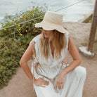 women's freya packable scallop crochet bucket hat in natural on model outside by ocean