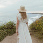 women's freya packable scallop crochet bucket hat in natural on model outside by ocean behind view