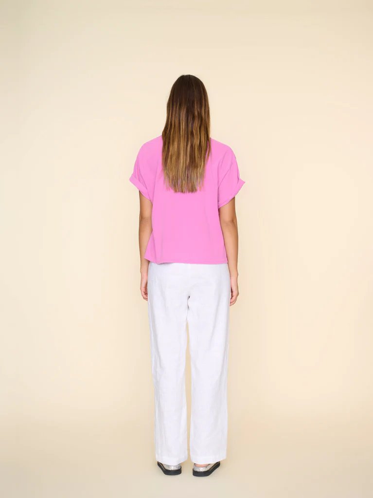 Behind view of xirena atticus pant in white worn on model with silver sandals and a pink tshirt